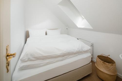 a bedroom with a bed with white sheets and a basket at Freywind easy in Norderney