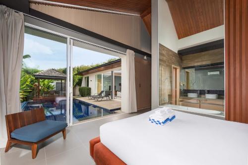 a bedroom with a bed and a large window at Solano Tropical 3BR Pool Villa at Bang Tao in Layan Beach