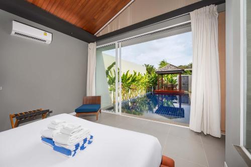 a bedroom with a bed and a large window at Solano Tropical 3BR Pool Villa at Bang Tao in Layan Beach