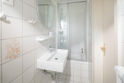 a white bathroom with a sink and a mirror at Freywind easy in Norderney