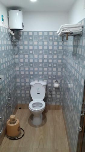 a bathroom with a toilet in a tiled wall at Radharani Kutir , Nabadwip in Navadwīp