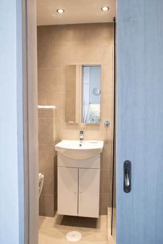 a bathroom with a white sink and a mirror at Panoramic Seaview Maisonette with Garden in Saronida