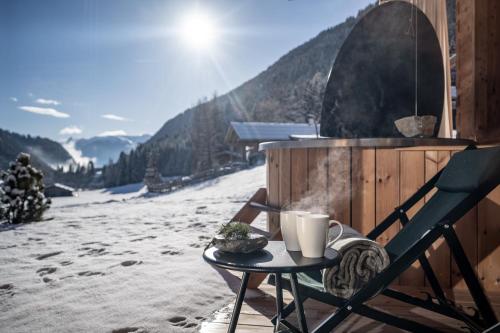 a table with a cup of coffee on top of a snow covered slope at Valsegg Chalets Südtirol - luxury and private hideaway in Valles