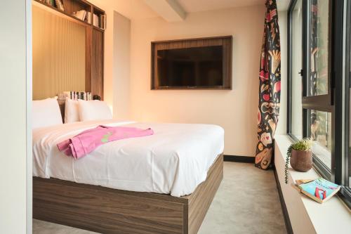a bedroom with a bed with white sheets and a tv at JOST Hôtel Lille Centre in Lille