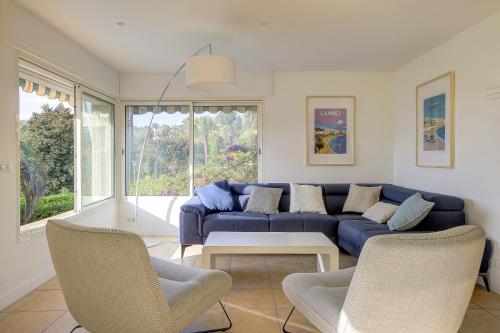 un salon avec un canapé bleu et des chaises dans l'établissement Villa rénovée- Vue mer- Centre de Cannes, à Cannes