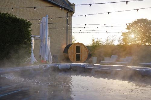 a pool of water with a umbrella and an infront of a house at Bicester Hotel, Golf & Spa in Bicester