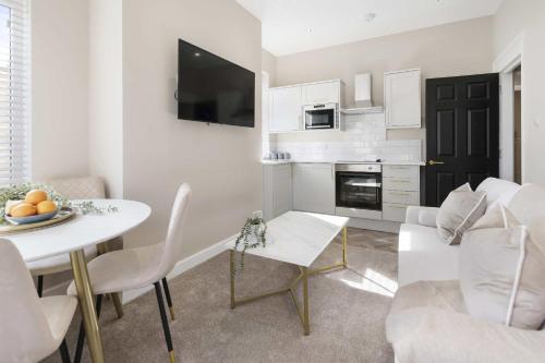 a white living room with a table and a couch at The Park Road Suites by Central Beach Leisure in Blackpool