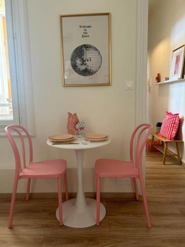 une table avec deux chaises roses et une table blanche avec une table et deux chaises dans l'établissement L'etage-30m2 au coeur d'un immeuble haussmannien, à Sète