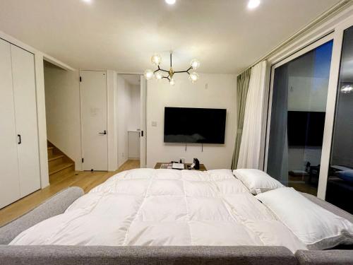 a large white bed in a bedroom with a tv at Niseko White Villas I in Kombu