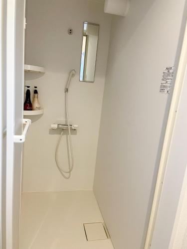a shower in a white bathroom with a window at Niseko White Villas I in Kombu