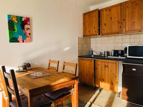 a kitchen with a wooden table and a microwave at Repülőhal Apartmanház in Zebegény