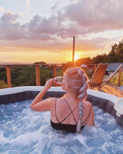 a woman in a hot tub drinking a glass of wine at Vineyard Cottage Sončni grič in Trebnje