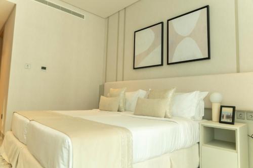 a white bedroom with a large white bed at Pearlhouse Bahrain in Manama