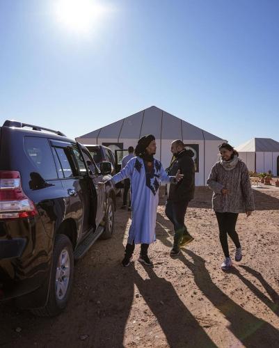 a group of people standing next to a car at Merzouga Berbers Luxury Camp in Merzouga