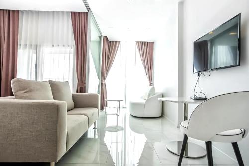 a living room with a couch and a table and a tv at Hyde Sukhumvit 11 Bangkok in Bangkok