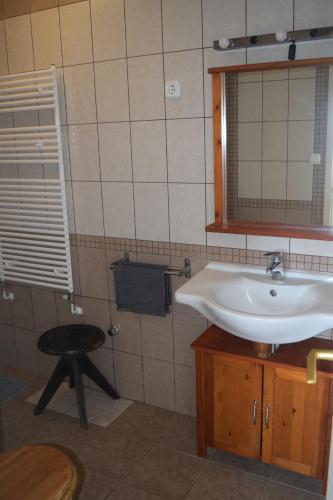 a bathroom with a sink and a mirror and a stool at Repülőhal Apartmanház in Zebegény