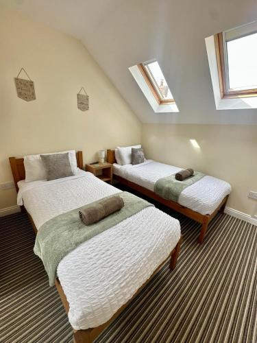 two beds in a room with two windows at Welbury Studio Retreat - Sleeps 2 in Northallerton