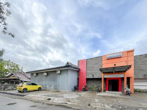 a yellow car parked in front of a building at RedDoorz at Krisan Kendari in Pulupanda