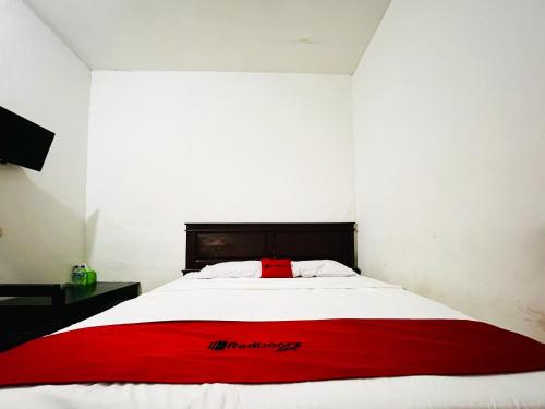 a red blanket on a white bed in a room at RedDoorz at Krisan Kendari in Pulupanda