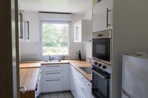 eine Küche mit weißen Schränken, einer Spüle und einem Fenster in der Unterkunft PeaceHome in Courbevoie