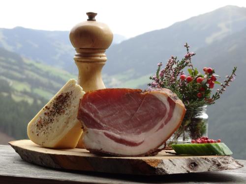 a piece of meat on a cutting board with fruit at Pension Forsthof in Maishofen