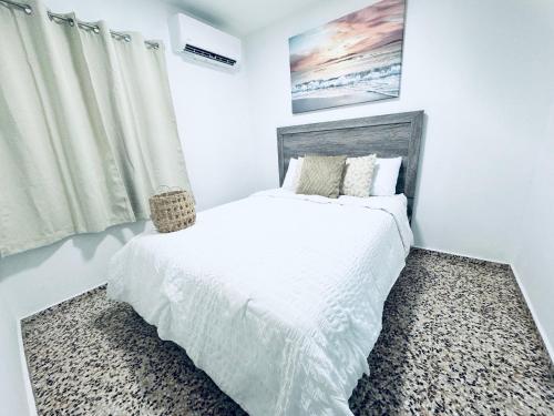 a white bedroom with a bed and a window at GD Vacation Rentals in Arecibo