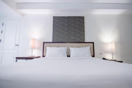 a bedroom with a large white bed with two lamps at Romance Hotel Bangna in Bangkok