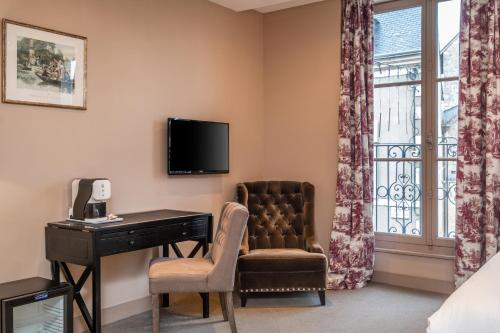 a hotel room with a desk and a chair and a window at Hostellerie de l'Écu de Bretagne in Beaugency
