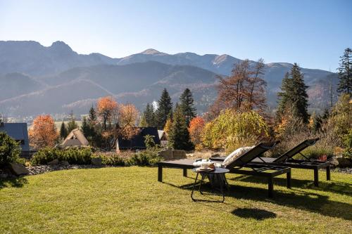 a picnic table in a field with mountains in the background at Villa La Roca Garden and Spa in Kościelisko
