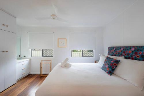 1 dormitorio blanco con 1 cama blanca grande y 2 ventanas en Little Banksia 1 - LJHooker Yamba, en Yamba