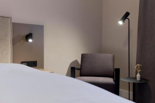 a bedroom with a bed and a chair and a lamp at Hotel Müllerbräu in Pfaffenhofen an der Ilm