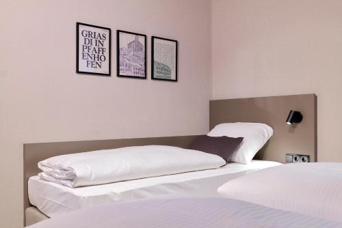 a bedroom with two beds and three pictures on the wall at Hotel Müllerbräu in Pfaffenhofen an der Ilm