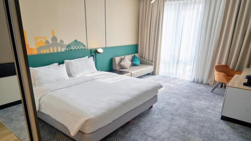 a hotel room with a large bed and a chair at Holiday Inn Tashkent City by IHG in Tashkent