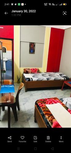 a room with two beds and a table and a mirror at Pulu Restaurant & lodge in Majuli