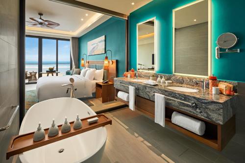 a bathroom with a large tub and a bedroom with a bed at Angsana Quan Lan, Ha Long Bay in Quan Lạn