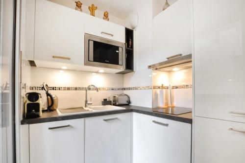 une cuisine avec des armoires blanches et un micro-ondes dans l'établissement Nice studio for two close to the beaches of Cannes, à Cannes