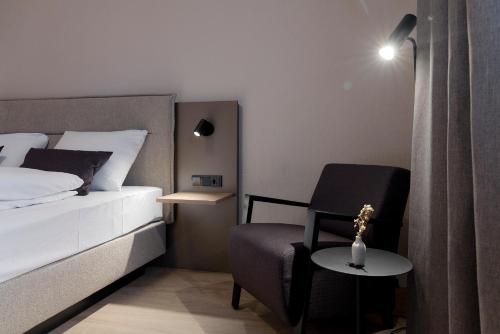 a bedroom with a bed and a chair and a table at Hotel Müllerbräu in Pfaffenhofen an der Ilm