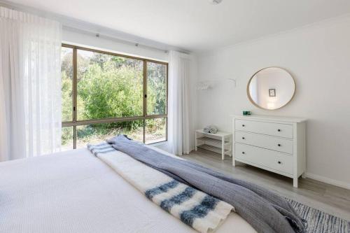 a white bedroom with a bed and a mirror at Capewood - Coastal Family Retreat in Prevelly in Prevelly