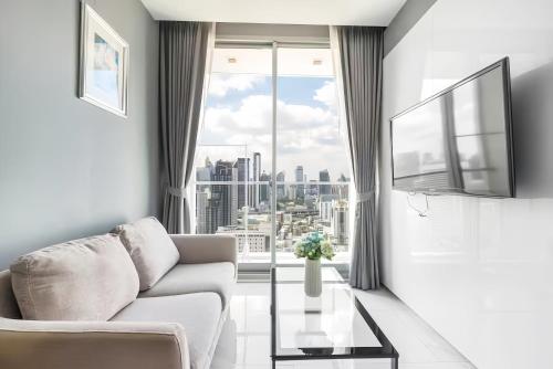 a living room with a couch and a large window at Hyde Sukhumvit 11 Bangkok in Bangkok