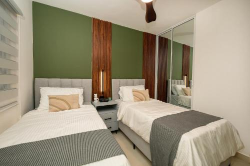 two beds in a room with green walls and mirrors at Pool & Gym - 10min Aeropuerto y HOMS - Dream Stay in Santiago de los Caballeros