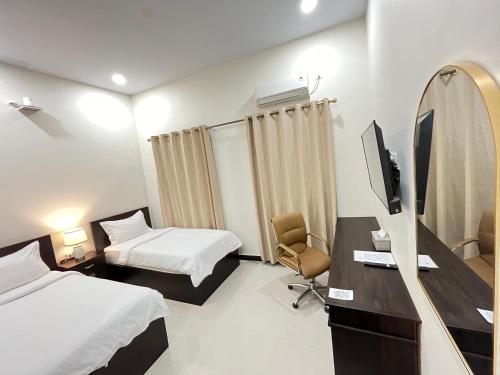 a hotel room with two beds and a desk with a tv at DJ Hotel in Raha