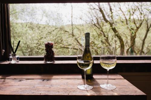 two glasses of white wine sitting on a table next to a window at A Place In the Pennines in Huddersfield