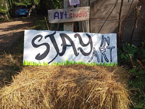 a sign that says stay in art on a pile of hay at Stay in art studio guesthouse in Kampong Huaibū