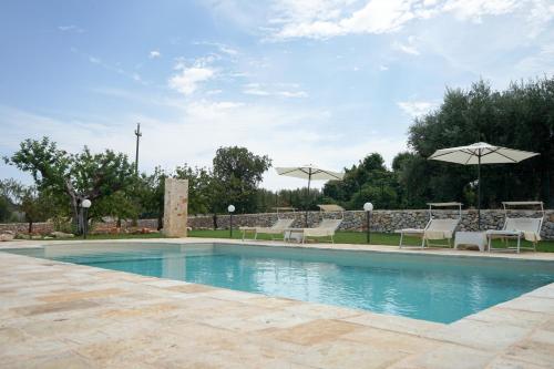 a swimming pool with chairs and umbrellas at Quattroperle Trulli - Relax - Puglia in Castellana Grotte