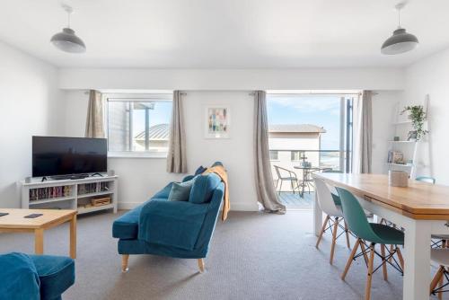 a living room with a blue chair and a table at Spacious Flat Sea Views & Private Parking Fistral in Newquay