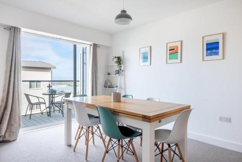 a dining room with a table and chairs and a balcony at Spacious Flat Sea Views & Private Parking Fistral in Newquay