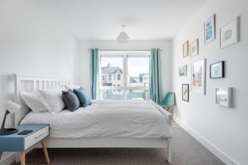 a white bedroom with a bed and a window at Spacious Flat Sea Views & Private Parking Fistral in Newquay