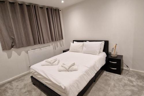 ウェンズベリーにあるSunset View-Luxury 2-Bed House Near Birminghamの白いシーツと枕が付いた大きなベッドのある寝室