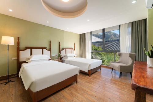 a bedroom with two beds and a desk and a chair at Serene Vale Inn Railway station free pick-up by 2 nights English and Spanish reception available in Guilin