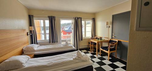 a hotel room with two beds and a desk at Hotel Lyngørporten in Gjeving